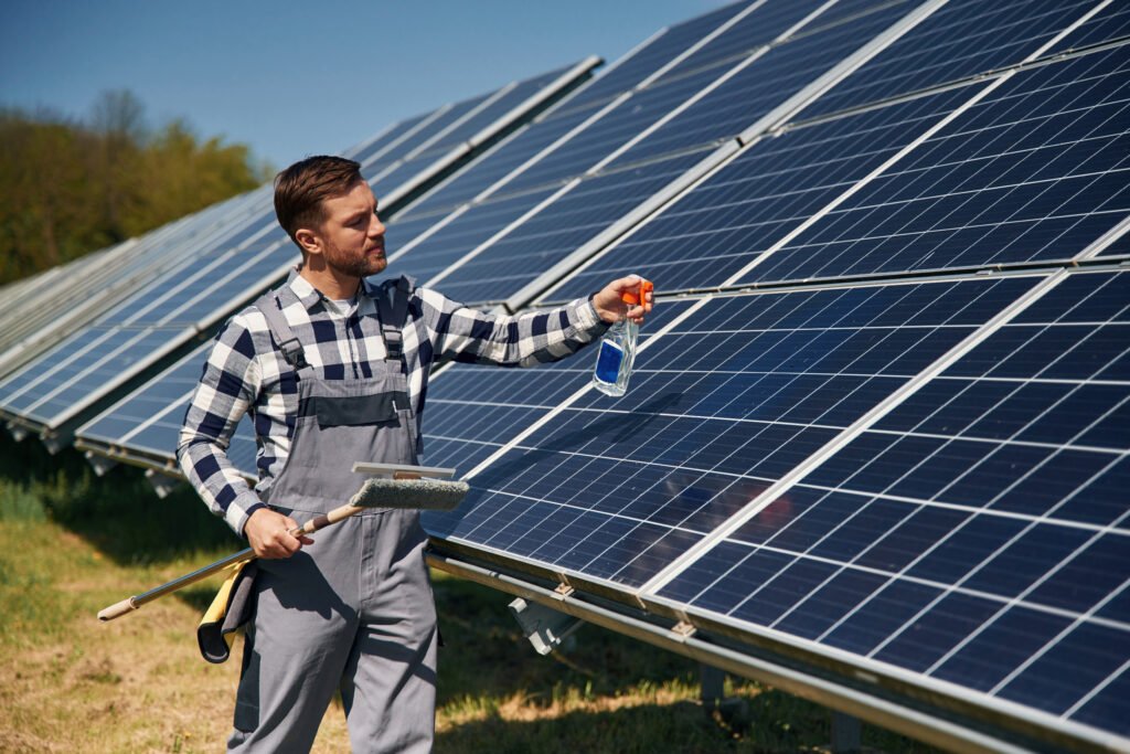 Procedure of cleaning the surface. Engineer with photovoltaic solar panels outdoors at daytime